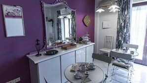 Ett modernt kök med vita skåp, ett matbord med stolar och en stor spegel ovanför köksbänken.