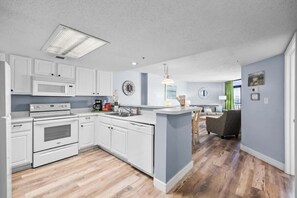 Una cocina moderna con armarios blancos, un microondas, un horno y una isla central.