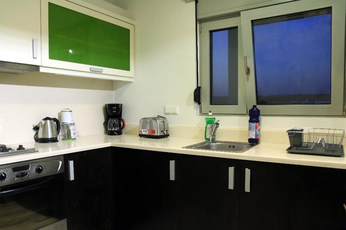 A kitchen with a stove, toaster, coffee maker, and a window with a view.
