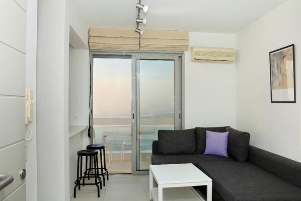 Ein modernes Wohnzimmer mit einer Couch, einem kleinen weißen Tisch und einem Balkon mit Blick.