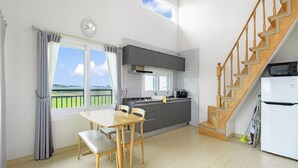 Une cuisine moderne avec des meubles de couleur grise, une table à manger en bois et un escalier.