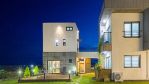 Un bâtiment moderne à deux étages, avec un chemin de pierre menant à un espace patio.