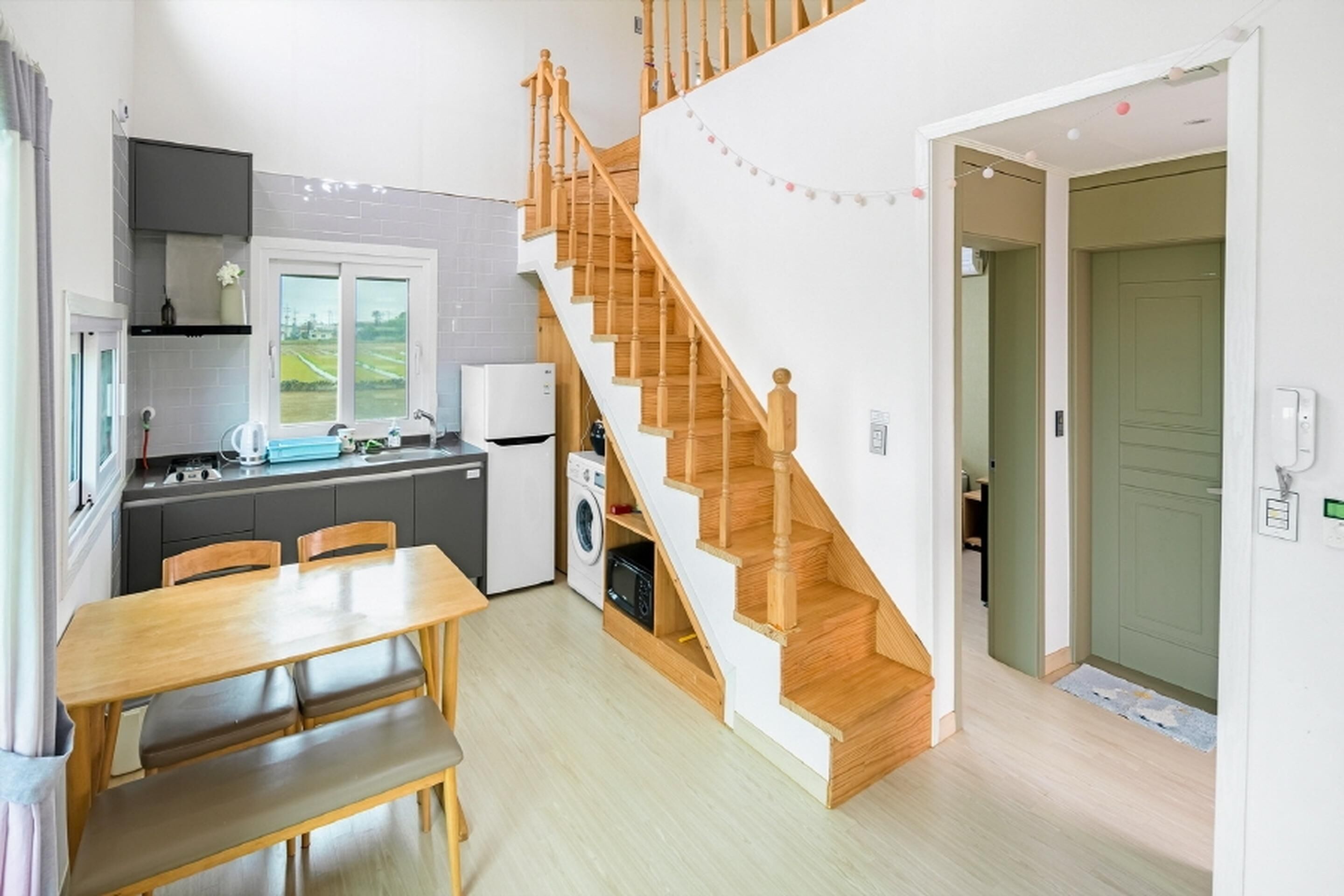 Cocina compacta con comedor, una escalera de madera y vistas al exterior.