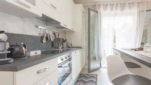 Une cuisine moderne avec des armoires blanches, un plan de travail noir et un four encastré.