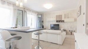 Une cuisine moderne avec un coin bar, un canapé et un téléviseur.