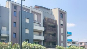 Un immeuble résidentiel à plusieurs étages, doté de balcons, avec un lampadaire et un ciel dégagé.