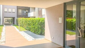 Un bâtiment moderne doté d’une porte en verre, d’un chemin piétonnier pavé et d’un arbuste taillé avec soin.