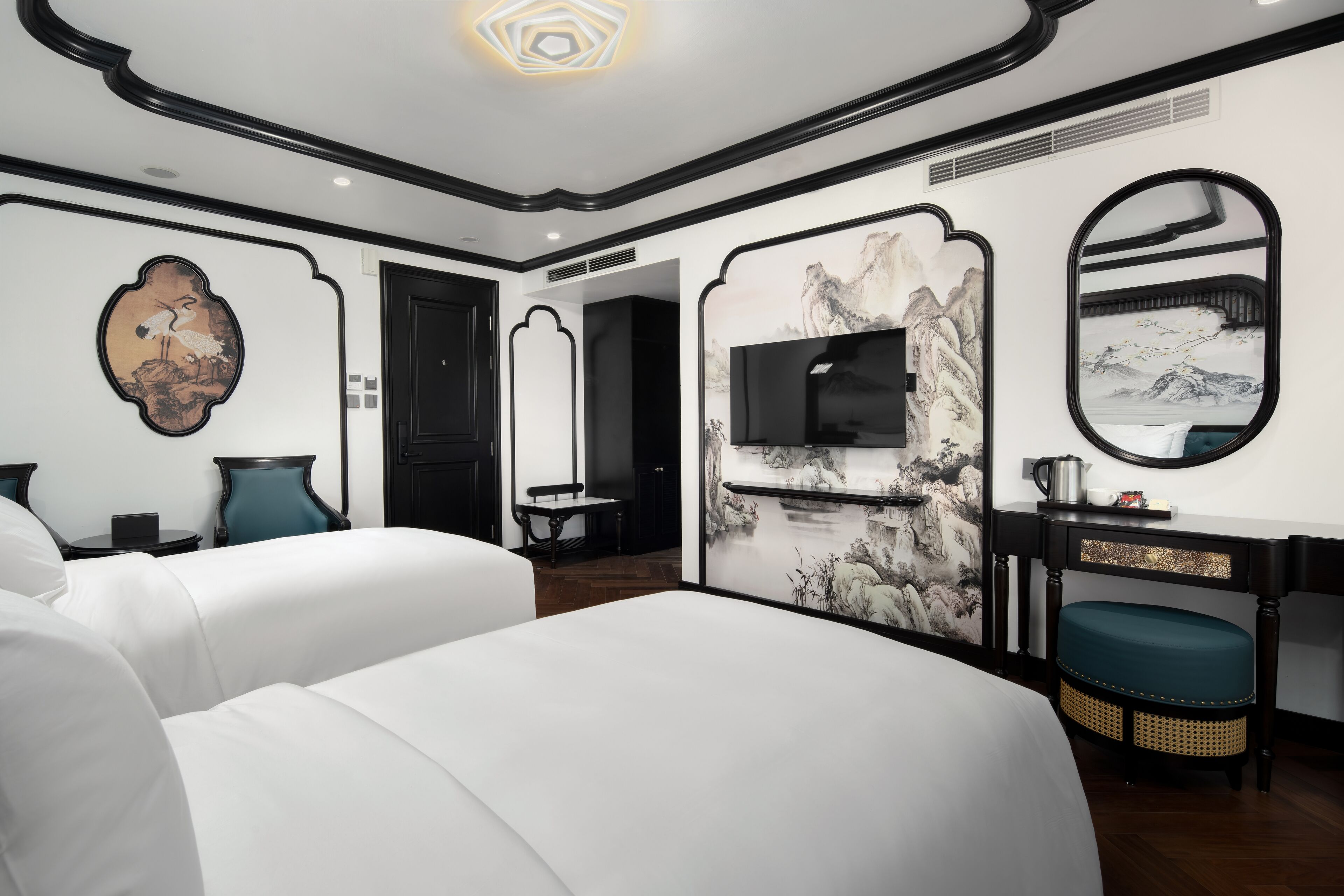 Een hotelkamer met twee bedden, een televisie, een bureau met stoel, en kunstwerken aan de muren.