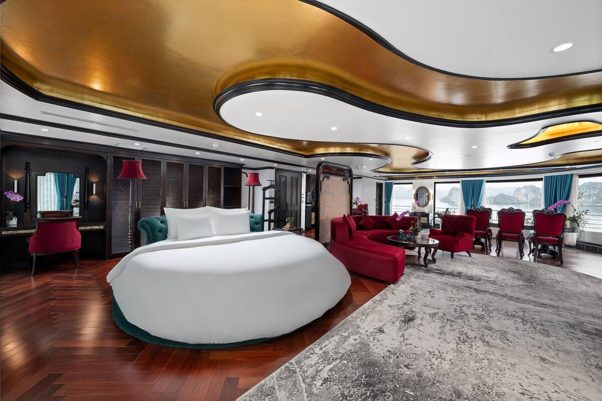 Ein luxuriöses Zimmer mit einem großen Bett, roten Sofas und Blick auf die Stadt.