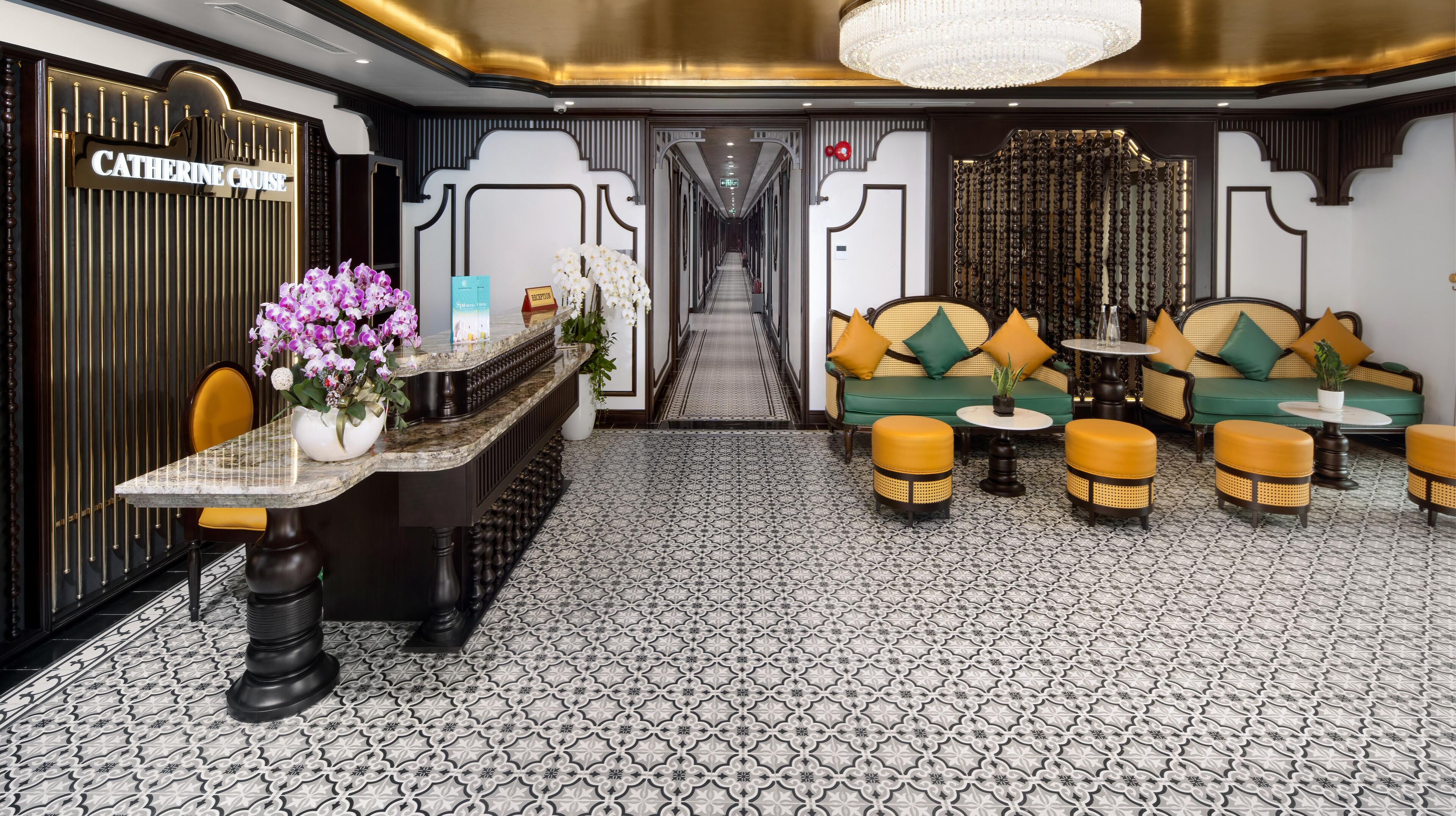 A reception area with a marble counter, a chandelier, and a sofa with yellow cushions.
