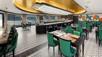 A restaurant with a bar area, green chairs, and a tiled floor.