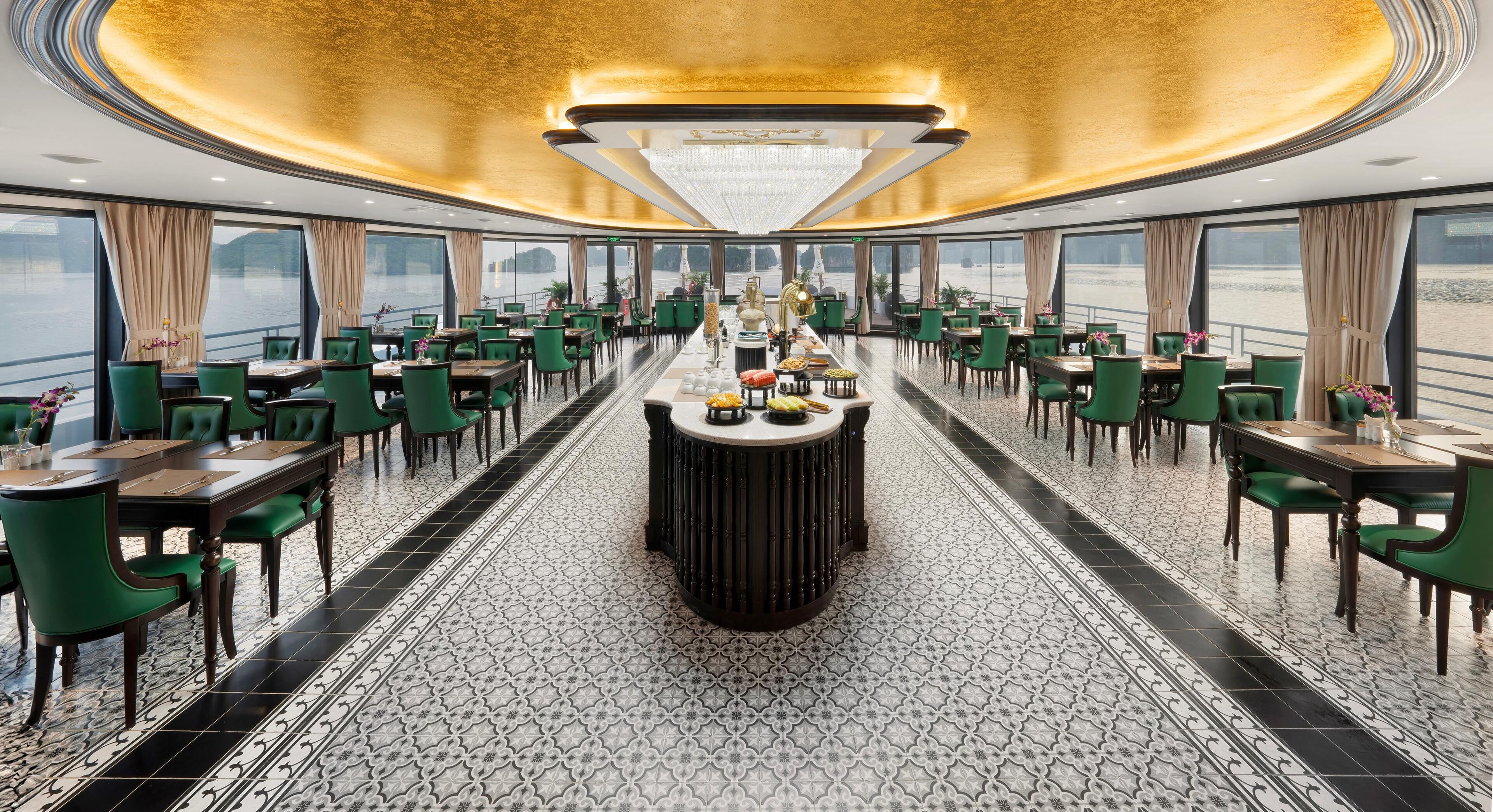 Ein luxuriöser Essbereich mit grünen, gepolsterten Stühlen und einer zentralen Bar.
