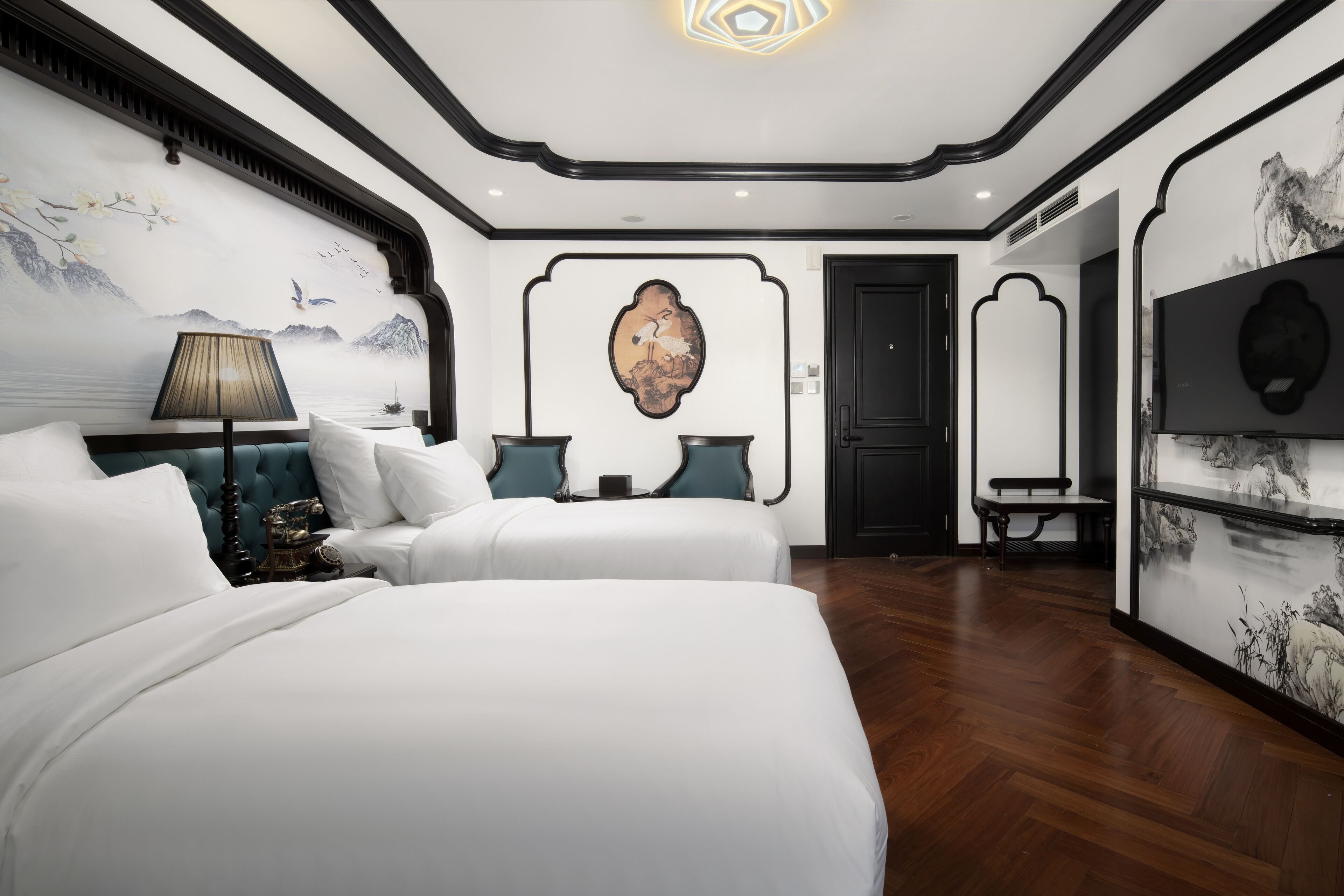 A hotel room with a large bed, a desk, and a chair. There is a painting on the wall and a window with curtains.