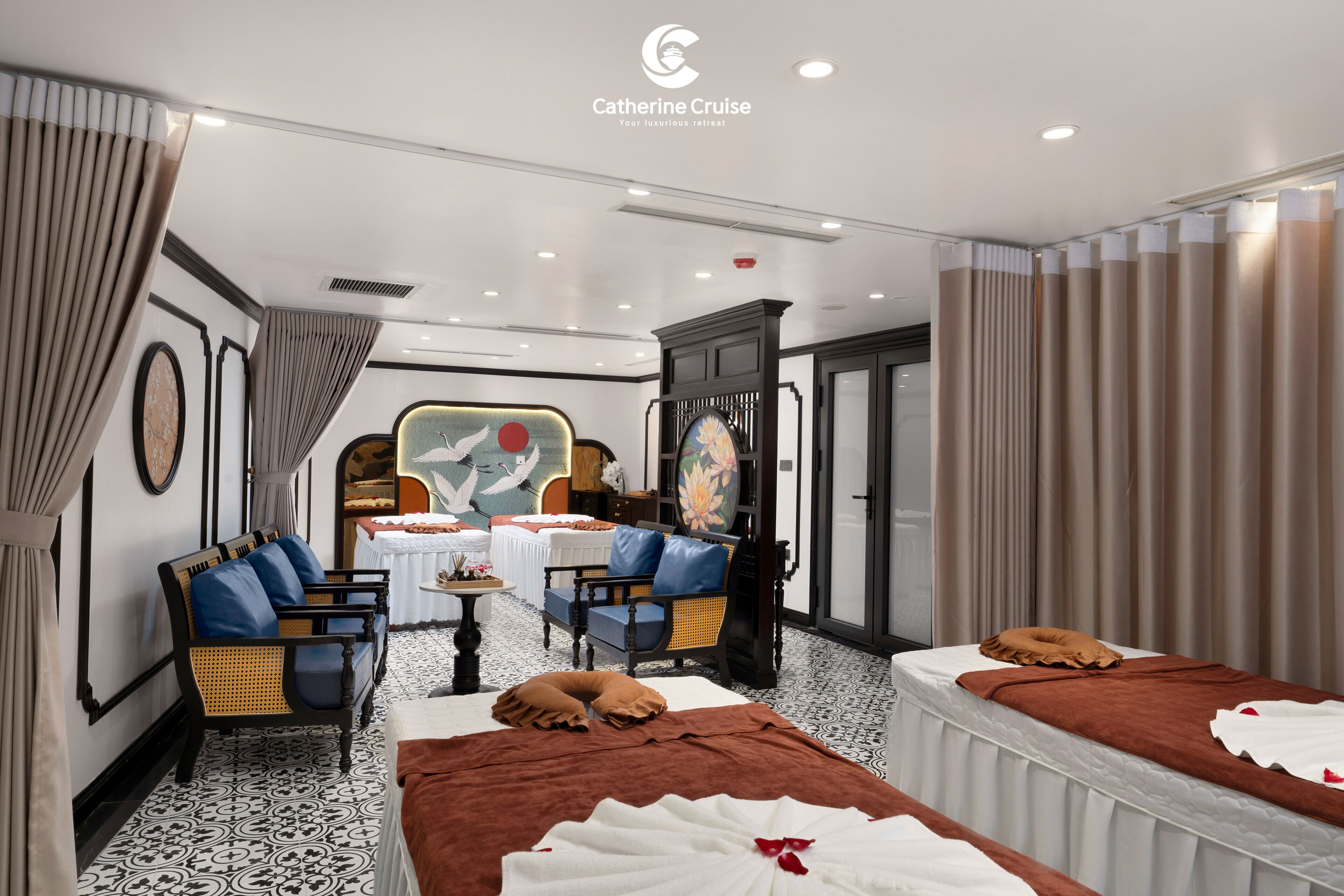 A hotel room with two beds, a dining table, chairs, and a massage table.