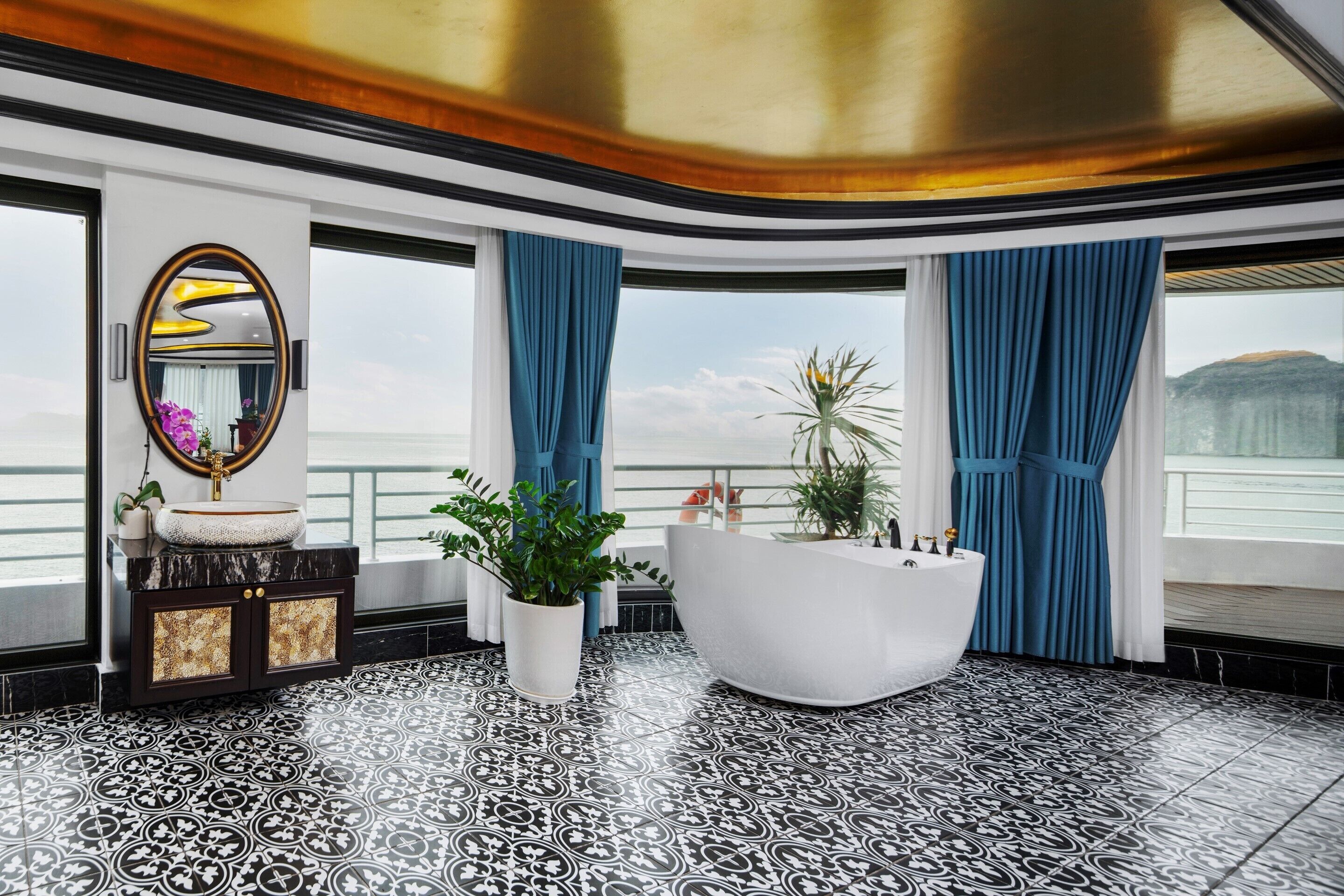 A luxurious bathroom with a large mirror, a white bathtub, and a potted plant.