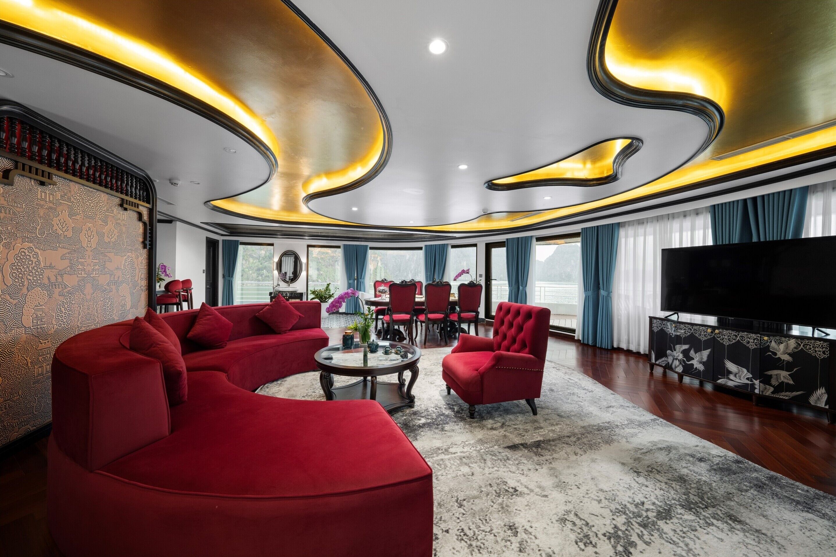 A modern living room with a curved ceiling, red sofas, a round coffee table, and a large flat-screen TV.