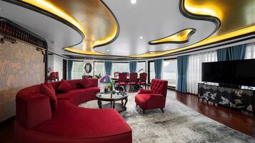 A modern living room with a curved ceiling, red sofas, a round coffee table, and a large flat-screen TV.