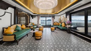 Un intérieur luxueux agrémenté d’un lustre, de canapés verts et d’un sol à motifs.