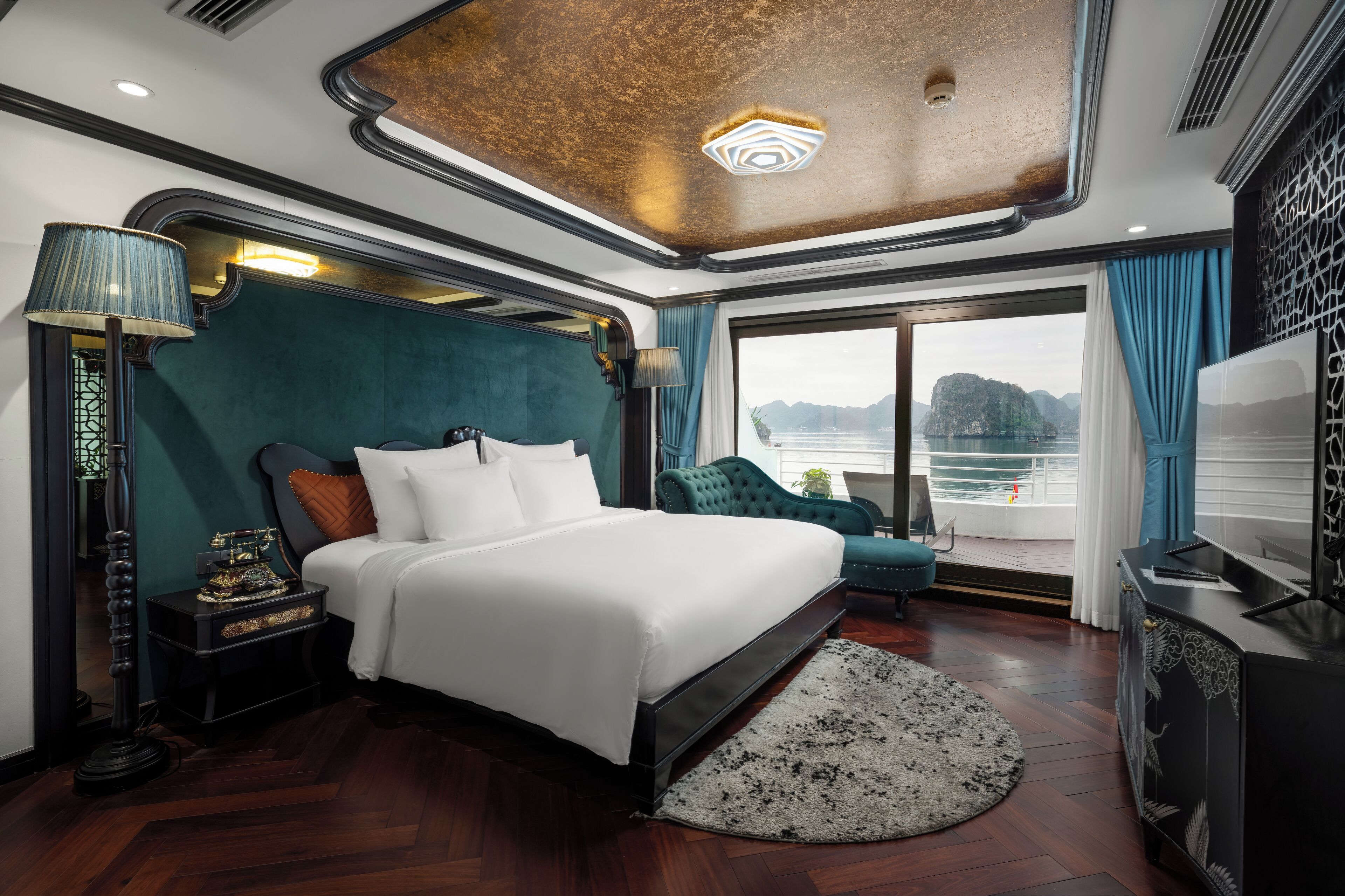 A modern hotel room with a large bed, a desk, a TV, and a view of the water.