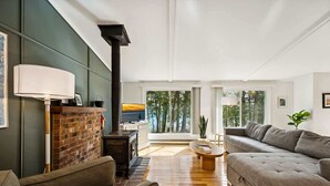 A spacious living room with a fireplace, a sofa, and a dining area. - Lake Michigan Cabin · Private Shoreline (Sturgeon Bay)