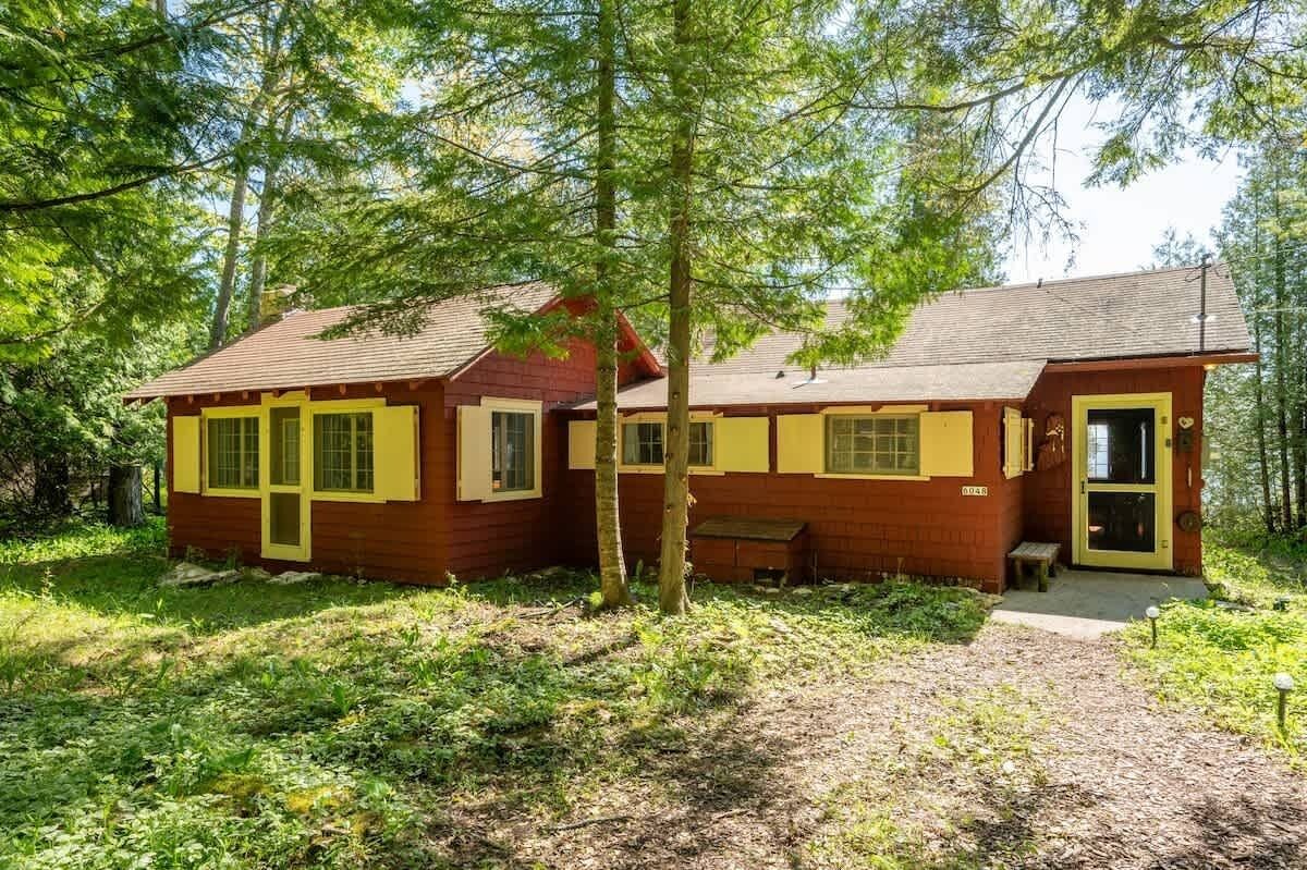 A cabin with a single-story structure, a front porch, and a door leading to the entrance.