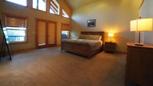 A bedroom with a bed, a nightstand, a lamp, and a framed picture on the wall. - Large Teton Family Home w/Hot Tub + Pool Table (Driggs)