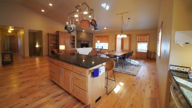 A spacious kitchen with wooden cabinets, a central island, and hanging pots. - Large Teton Family Home w/Hot Tub + Pool Table (Driggs)