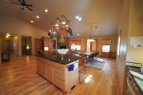 A spacious kitchen with wooden cabinets, a central island, and hanging pots.