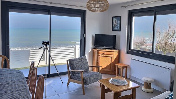 A balcony with a view of the sea, a telescope, a TV, and seating.