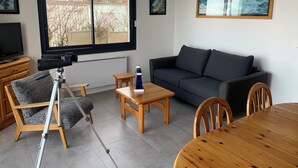 A modern living room with a sofa, a dining table, and a telescope.