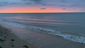 A beach with a calm sea and a sunset sky.