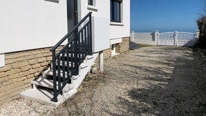 A white building with a stone foundation, a black staircase, and a gated entrance.