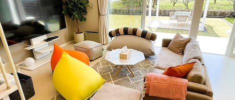 Relax in this stylish living room with a large flat-screen TV, comfortable sofa, and garden views.
