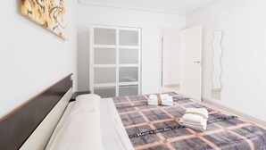 Moderni hotellihuone, jossa on sänky, suuri peili ja vaatekaappi.