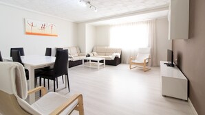 Moderni olohuone, jossa on ruokailutila, sohva, televisio ja katto, jossa on geometrinen kuvio.