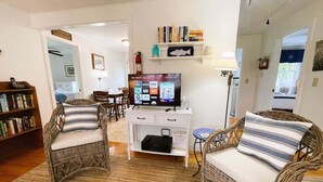 Ein Wohnzimmer mit Korbmöbeln, einem Fernseher und einem Bücherregal.