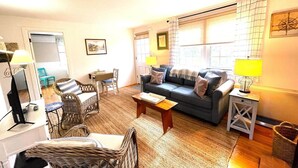 Ein gemütliches Wohnzimmer mit einer Couch, Sesseln, einem Couchtisch und einer Lampe.