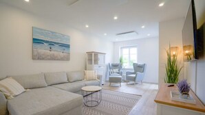 Una sala de estar moderna con un sofá seccional gris, dos sillones, una mesita redonda y una alfombra decorativa.