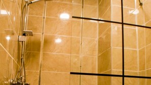 A modern bathroom with a shower, a toilet, and a tiled floor. - Ekin Otel (Fethiye)