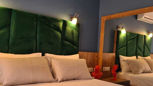 A hotel room with a large bed, a wooden headboard, and a mirror. There are two bedside tables with candles. - Ekin Otel (Fethiye)