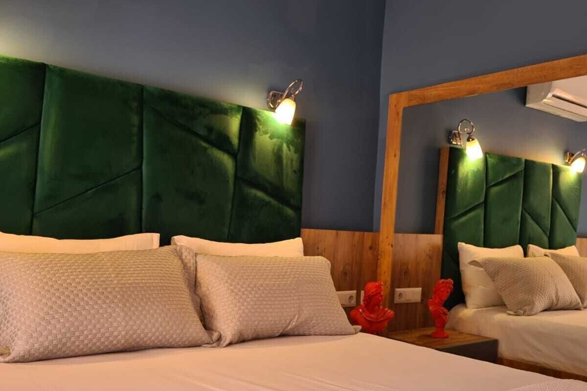 Habitación de hotel con una cama grande, dos mesitas de noche, un espejo y aire acondicionado instalado en la pared.