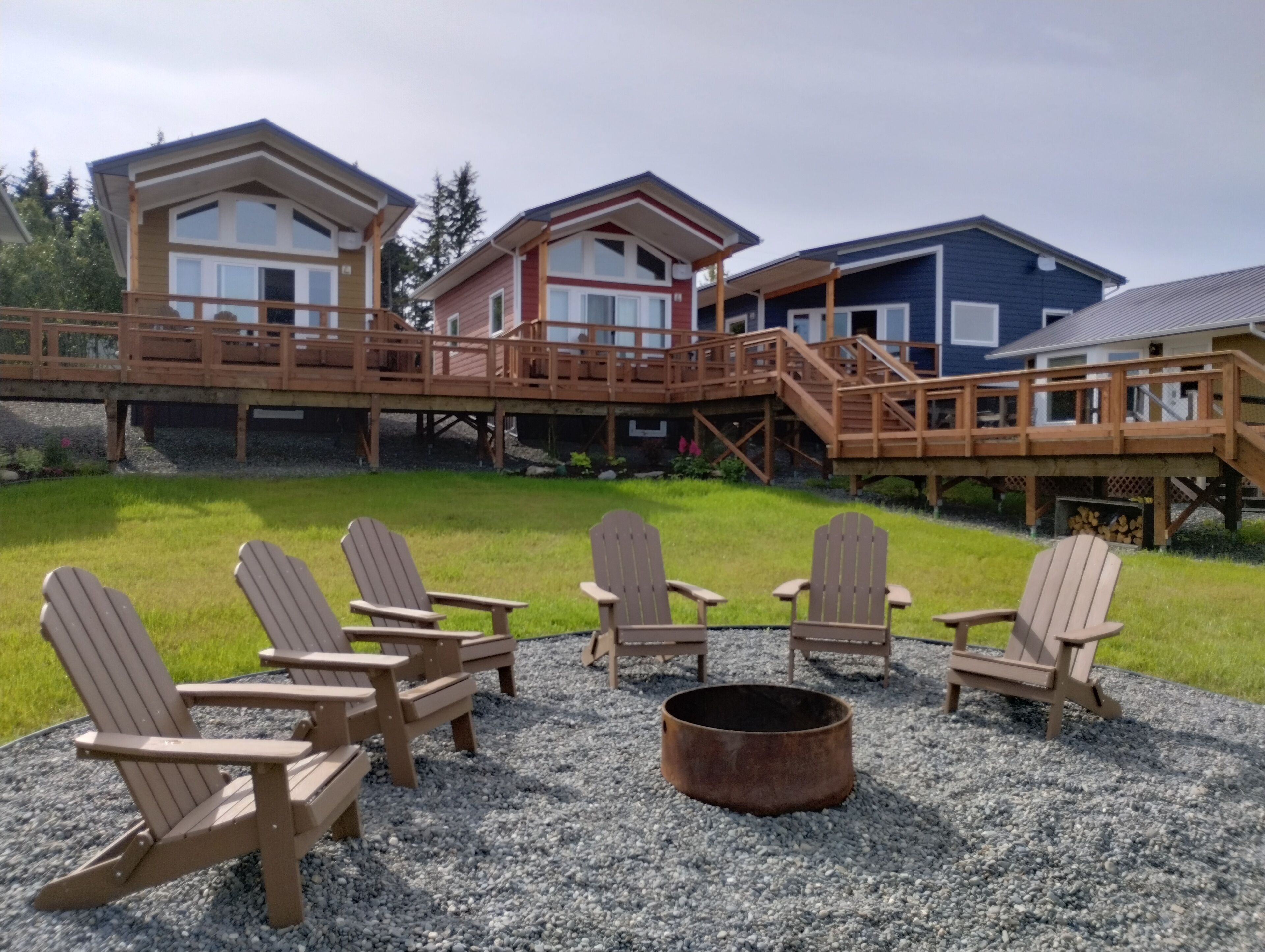 Eine Hütte mit einer Terrasse, Sitzgelegenheiten im Freien und einer Feuerstelle.