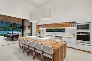 Una cocina moderna con una isla central, muebles blancos y electrodomésticos de acero inoxidable.