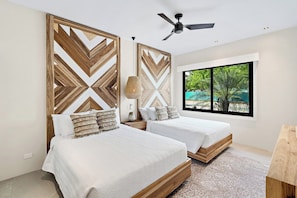 A bedroom with two beds, a ceiling fan, a large window with a view, and a wooden headboard design. - Casa Maui (Reserva de Golf, Hacienda Pinilla)