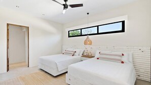 Une chambre avec deux lits, un ventilateur de plafond, une fenêtre avec vue et une table de chevet avec une lampe.