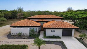 Une maison moderne avec un toit en tuiles, un garage et un jardin aménagé.