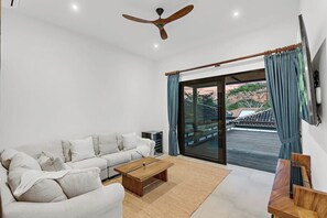 A modern living room with a sofa, coffee table, and a TV mounted on the wall. - Rancho Alegre (Los Almendros, Hacienda Pinilla)