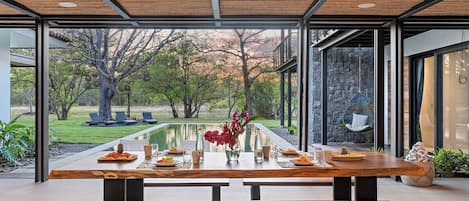 A dining area with a wooden table and benches, a view of the outdoors, and a ceiling fan.