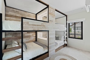 A modern bedroom with bunk beds, a large window, and a view of the outdoors.