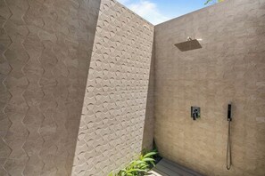 A shower area with a textured wall and a handheld showerhead.